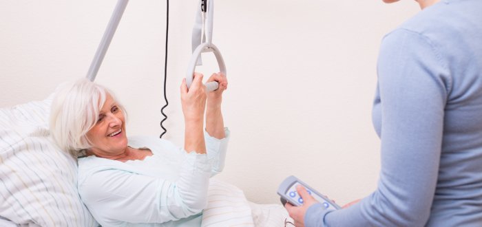 Seniorin im Krankenbett mit Pflegerin