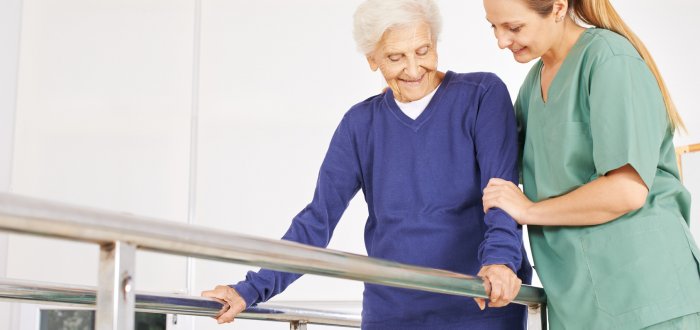 Physiotherapeutin hilft Seniorin auf Laufband