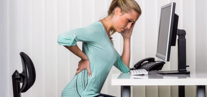 Frau mit Rückenschmerzen im Büro