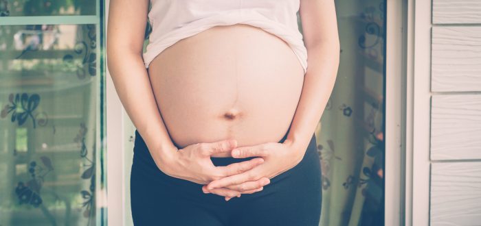 close up hand pregnant woman holding her tummy